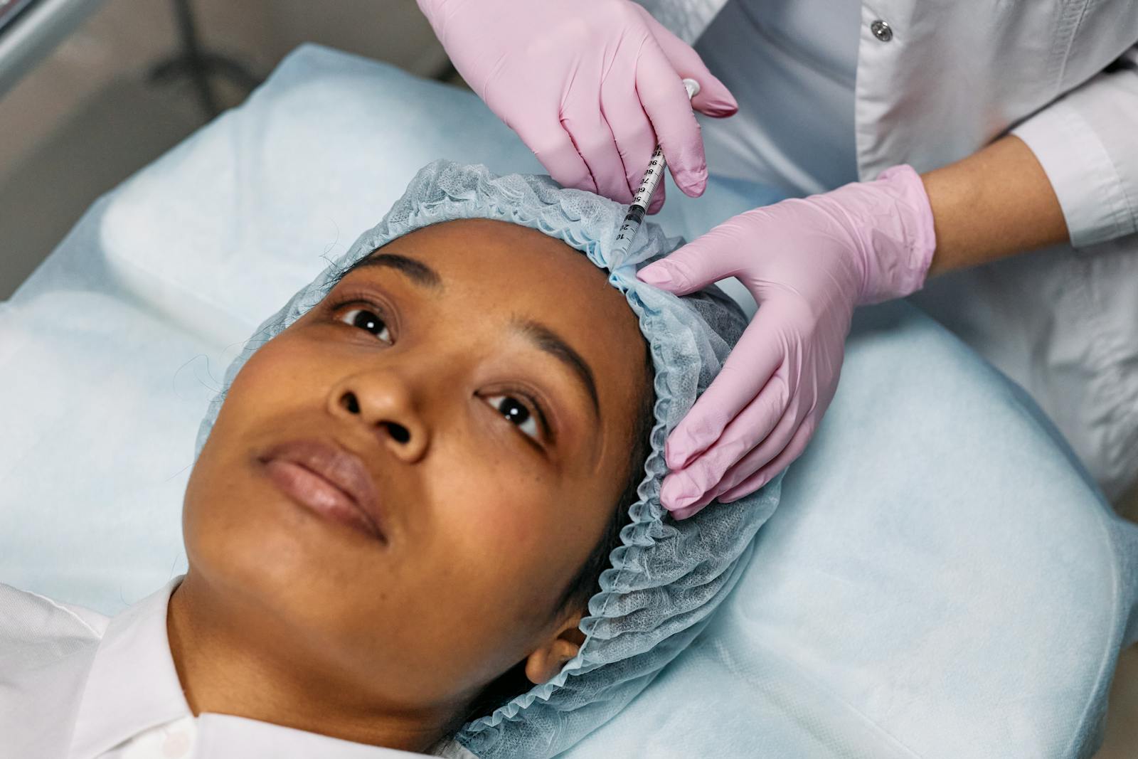 Close-up of a cosmetic procedure using injectables on a woman's forehead in a clinic setting.