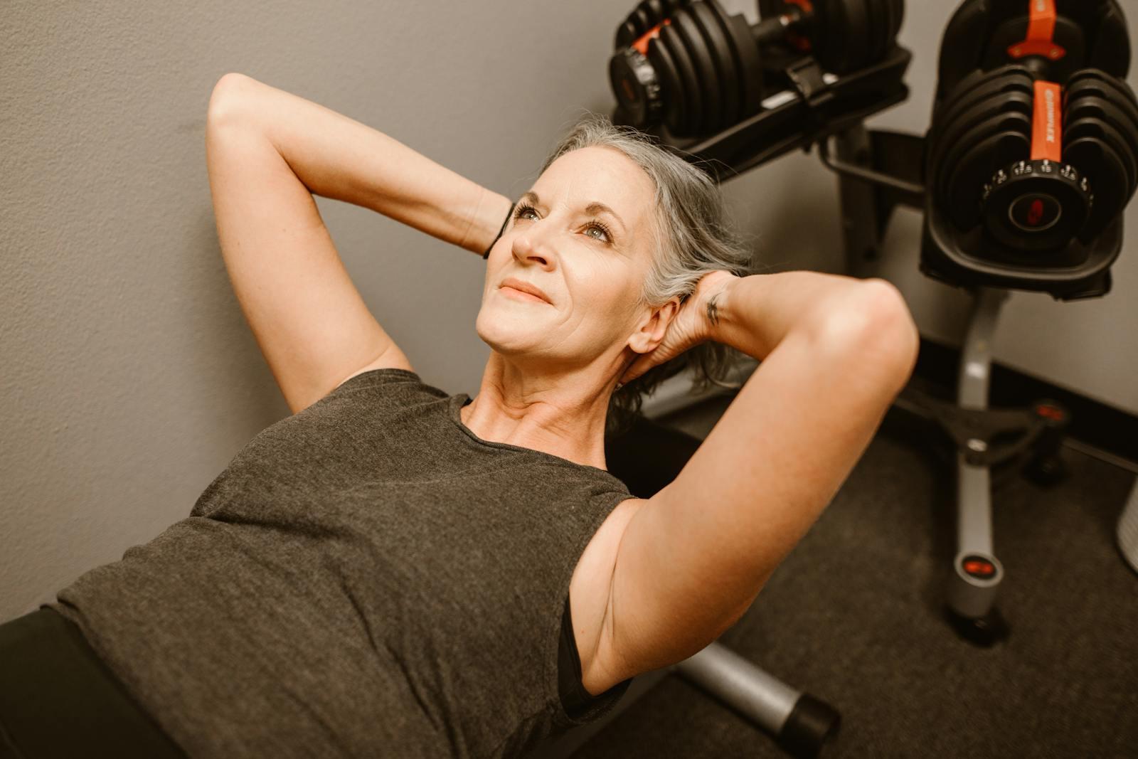 A senior woman performing exercises with dumbbells in a modern fitness center, promoting active lifestyle.